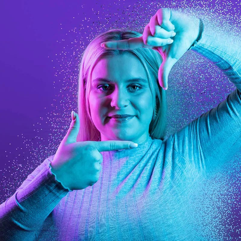 Frau rahmt ihr Gesicht mit ihren Fingern ein und lacht für Imagekampagne in die Kamera