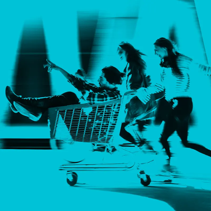 Drei Personen rennen mit einem Einkaufswagen für Imagekampagne